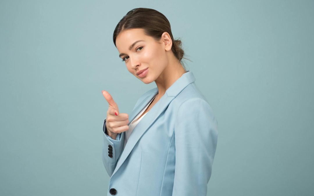 A person in a light blue blazer makes a finger-gun gesture against a blue background, evoking the vibrant energy of Orlando.
