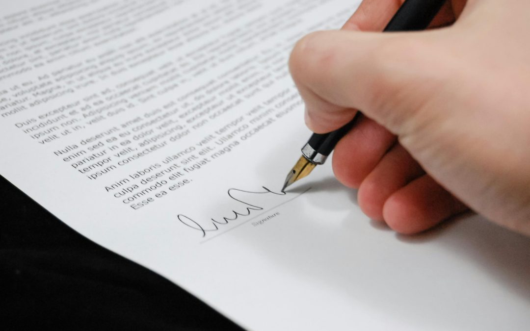 A hand signing a document with a fountain pen in Tampa; the paper contains dense text and a signature line at the bottom.
