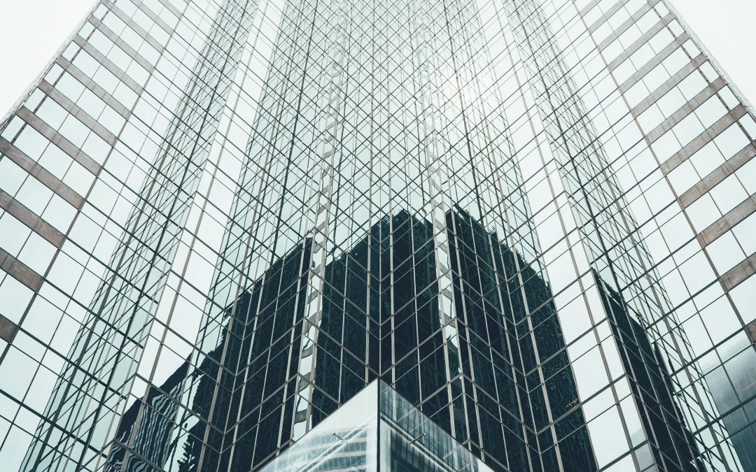 Low-angle view of a tall, glass skyscraper in Tampa with a reflective exterior, extending into a pale sky, capturing the building's modern architecture and geometric patterns.